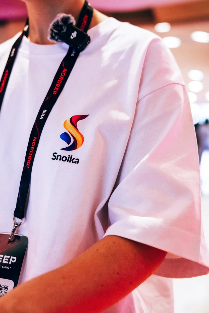 Close-up of the Snoika logo on a t-shirt with a NORDEEP lanyard