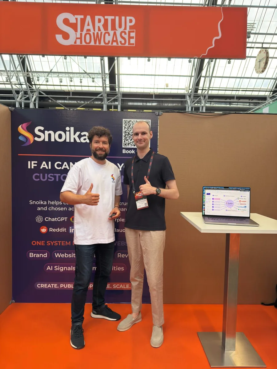 Two people at the Snoika stand next to a laptop demo